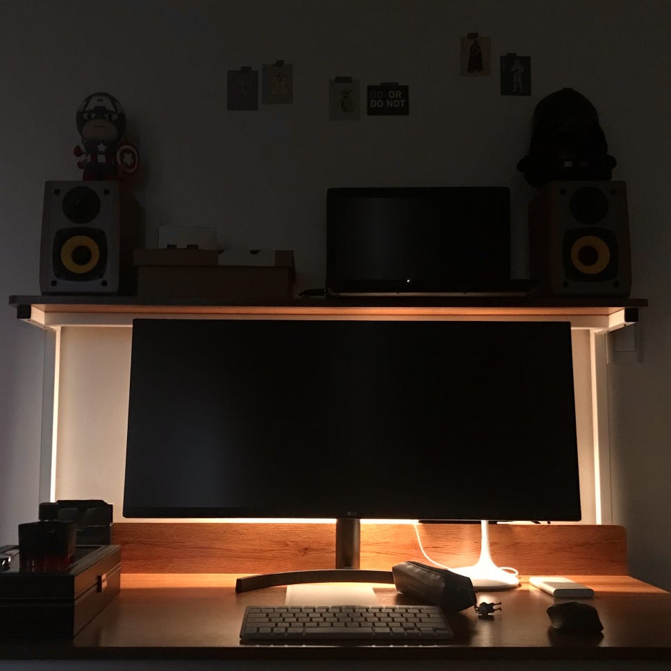 스피커와 키보드, 모니터가 놓인 선반 책상 사진.